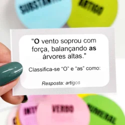 Jogo educativo de gramática com bolas coloridas e cartão de questão.