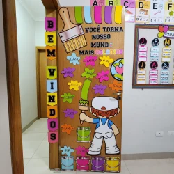 Porta afetiva colorida com nomes das crianças e elementos de pintura.