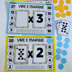Jogo educativo de multiplicação com cartas e marcadores coloridos.