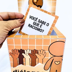 Caixa com mãos de diferentes cores e cartão com pergunta sobre racismo.