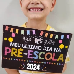 Criança feliz segurando cartaz de despedida da pré-escola.