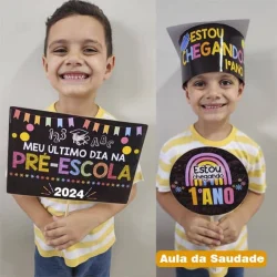 Crianças comemorando o primeiro ano na pré-escola com cartazes e chapéu de formatura.