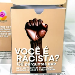 Caixa com livro sobre racismo e perguntas reflexivas para pensar.