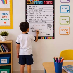Criança escrevendo regras de convivência na sala de aula.