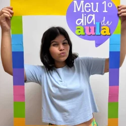 Criança segurando quadro de boas-vindas ao primeiro dia de aula.