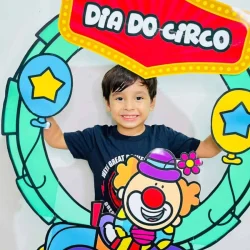 Criança com decoração de circo e bambolê colorido.