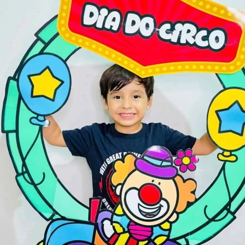 Criança sorridente com decoração de circo e bambolê na festa do Dia do Circo.