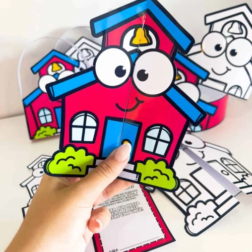 Lembrancinha de casa de escola com olhos e sorriso, feita de papel colorido.