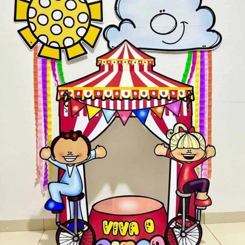 Moldura gigante de circo com crianças sorrindo e decoração colorida.