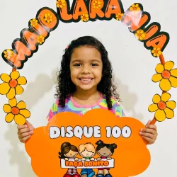 Criança sorridente segurando decoração de Maio Laranja com bambolê.