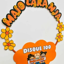 Guirlanda de bambolê decorada com flores e nome "Maio Laranja" para celebração.