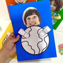 Criança segurando uma atividade com desenho do planeta Terra.