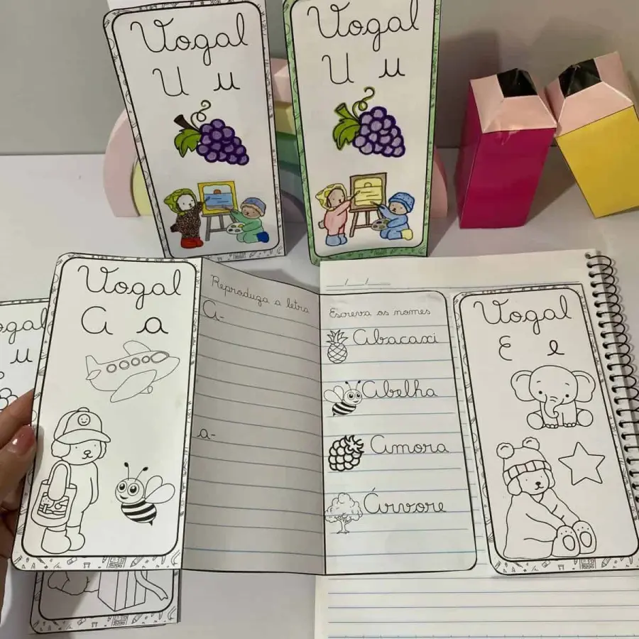 Cartões e caderno com atividades de vogais cursivas para crianças.