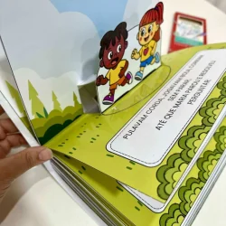 Livro infantil 3D com personagens coloridos sobre o corpo.
