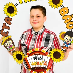 Criança com decoração de bambolê e tema junino para festa escolar.