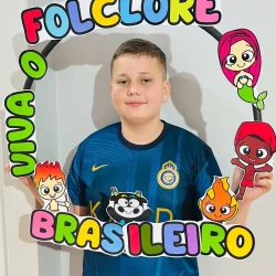 Menino com quadro de folclore brasileiro e personagens coloridos.