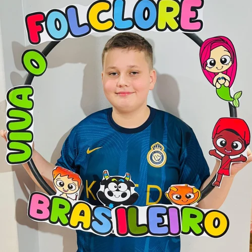 Menino segurando quadro com personagens do folclore brasileiro.
