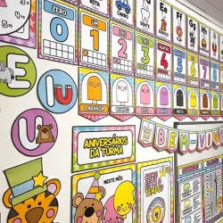 Painel educativo com letras, números e personagens infantis na sala de aula.