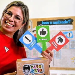 Mulher sorridente segurando sinais de amizade e cuidado em sala de aula.