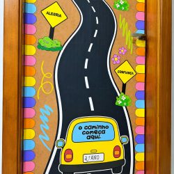 Porta decorada com estrada, sinais de trânsito e palavras positivas.