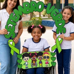 Crianças e professora com símbolo de Setembro Verde e bambolê na escola.