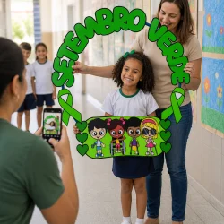 Criança com professora segurando cartaz de Setembro Verde na escola.